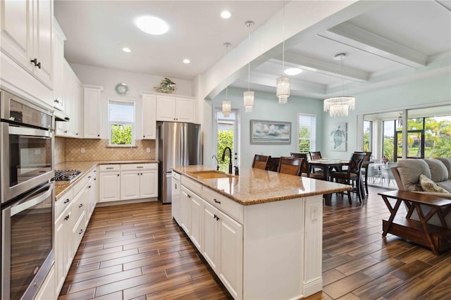 kitchen featuring a healthy amount of sunlight, sink, pendant lighting, and an island with sink