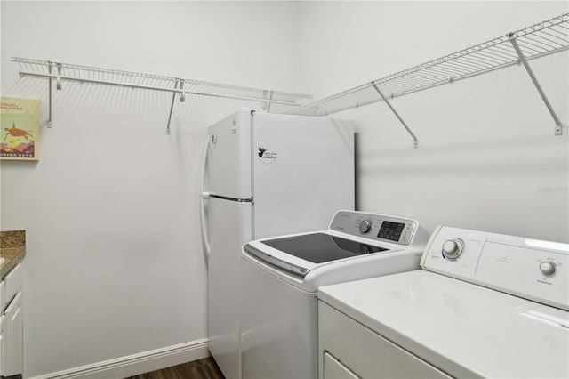 washroom with separate washer and dryer, dark hardwood / wood-style flooring, and cabinets