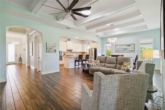 living room featuring ornamental molding, dark hardwood / wood-style floors, beamed ceiling, and plenty of natural light