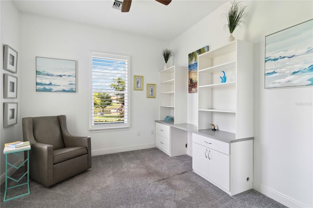 sitting room with built in desk, ceiling fan, and light colored carpet