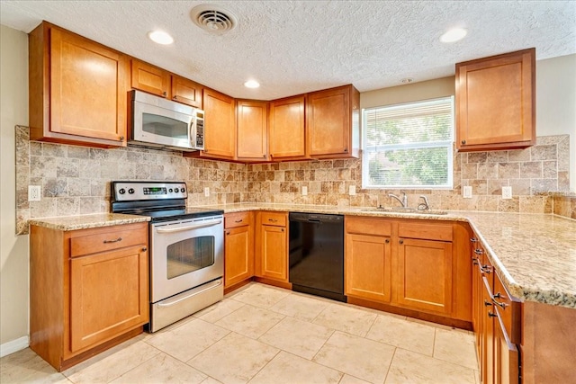 kitchen with a textured ceiling, sink, stainless steel appliances, and tasteful backsplash