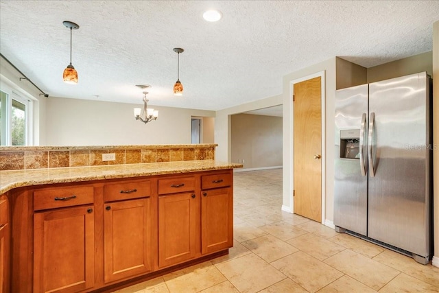 kitchen with a textured ceiling, light tile patterned floors, stainless steel fridge with ice dispenser, and decorative light fixtures