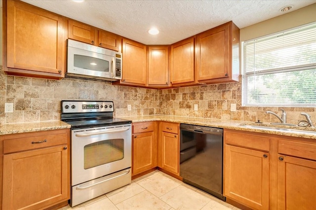 kitchen featuring appliances with stainless steel finishes, light stone countertops, light tile patterned floors, a textured ceiling, and sink