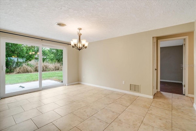 tiled empty room with a textured ceiling and a chandelier