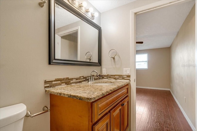 bathroom featuring tasteful backsplash, vanity, a textured ceiling, toilet, and hardwood / wood-style floors