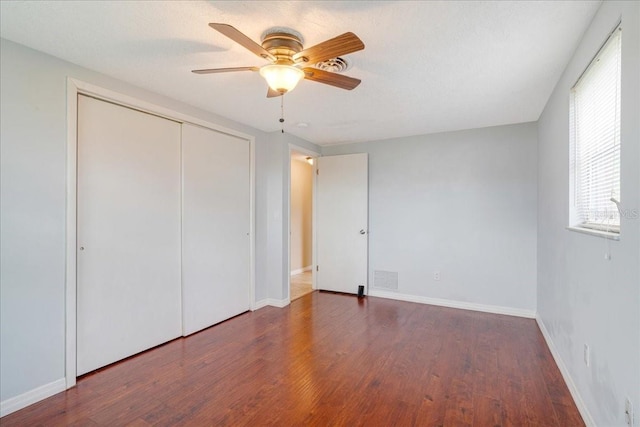 unfurnished bedroom featuring a textured ceiling, ceiling fan, dark wood-type flooring, and a closet