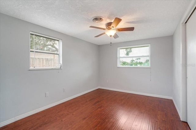 empty room featuring a textured ceiling, dark hardwood / wood-style flooring, and ceiling fan