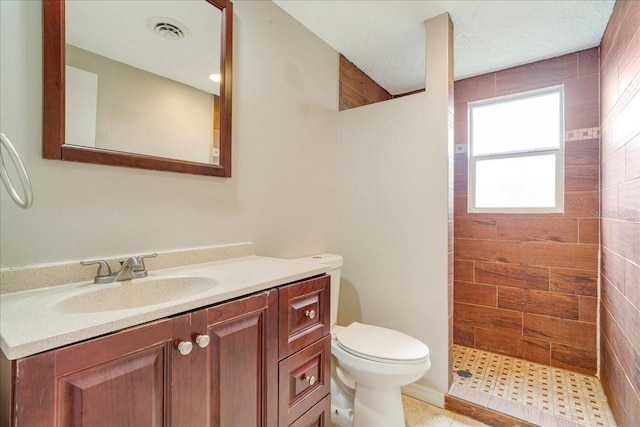 bathroom featuring tiled shower, a textured ceiling, vanity, and toilet