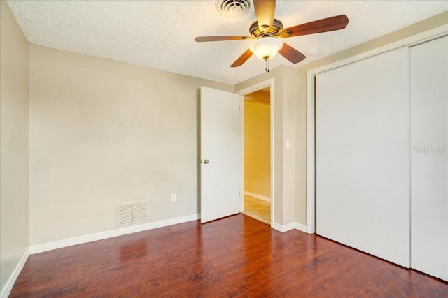 unfurnished bedroom featuring a textured ceiling, dark hardwood / wood-style floors, ceiling fan, and a closet