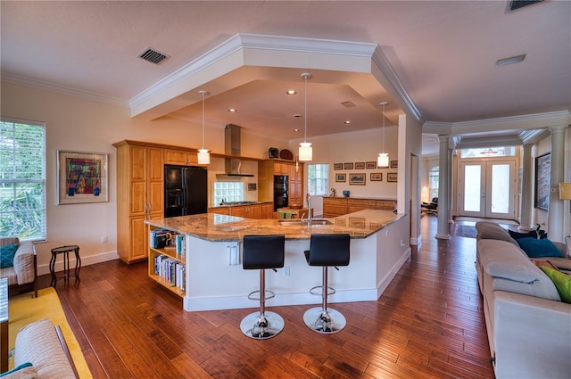 kitchen with a breakfast bar, hanging light fixtures, black fridge with ice dispenser, and a wealth of natural light