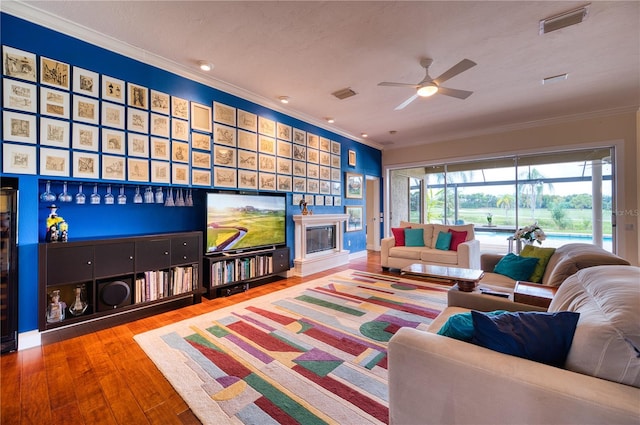 living room with wood-type flooring, ceiling fan, a textured ceiling, and crown molding