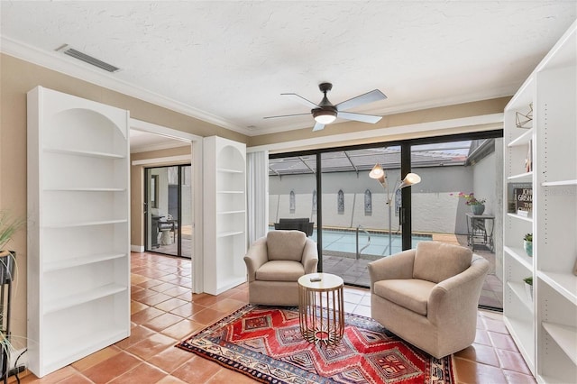 sitting room with visible vents, ornamental molding, a ceiling fan, a textured ceiling, and tile patterned floors