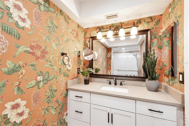 full bath featuring a shower, vanity, visible vents, and wallpapered walls