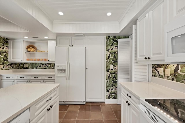 kitchen featuring white appliances, white cabinets, ornamental molding, light stone countertops, and dark tile patterned floors