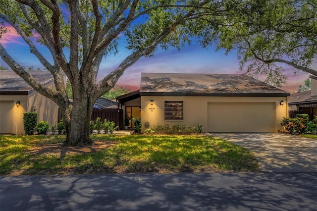 ranch-style house with a garage, concrete driveway, a lawn, and stucco siding