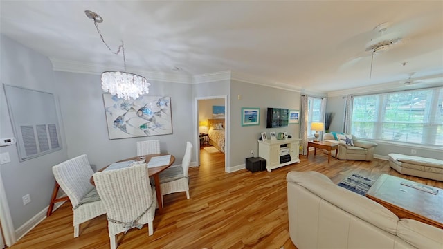 living room featuring ceiling fan with notable chandelier, light wood-type flooring, and crown molding