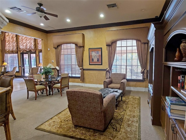 living area featuring ceiling fan, crown molding, and light carpet