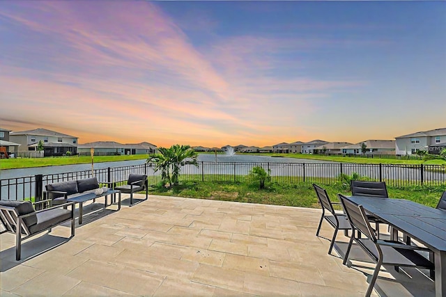 patio terrace at dusk with a water view and a yard