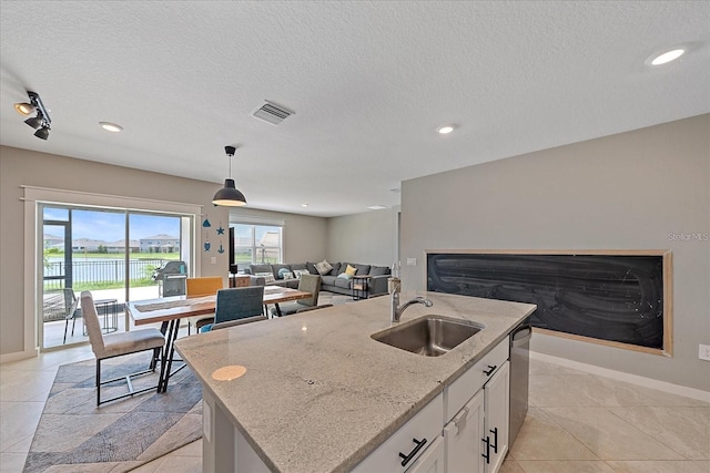 kitchen with white cabinets, plenty of natural light, a kitchen island with sink, and sink