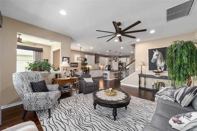 living room with ceiling fan, dark wood-type flooring, and a textured ceiling