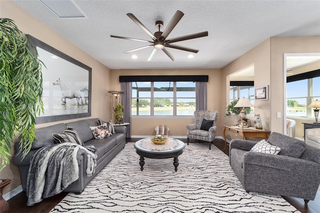 living room featuring a textured ceiling, hardwood / wood-style flooring, and ceiling fan