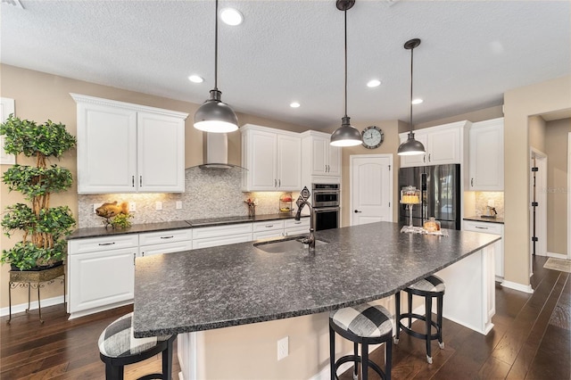 kitchen featuring a large island with sink, white cabinets, sink, appliances with stainless steel finishes, and dark hardwood / wood-style flooring