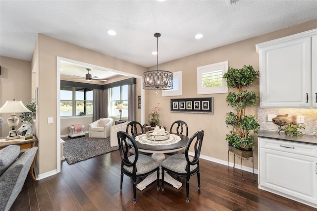 dining area featuring a textured ceiling, ceiling fan with notable chandelier, and dark wood-type flooring