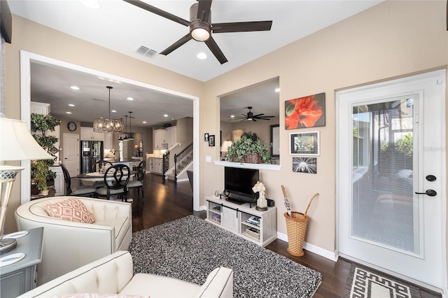 living room with dark hardwood / wood-style flooring and ceiling fan with notable chandelier