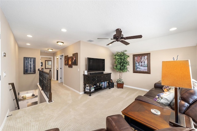 living room featuring ceiling fan, light colored carpet, and a textured ceiling