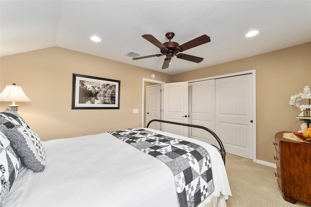 carpeted bedroom with a closet, lofted ceiling, and ceiling fan