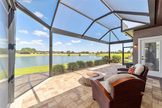 view of patio with a lanai, a water view, and an outdoor fire pit