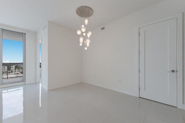 unfurnished room featuring an inviting chandelier and light tile patterned floors