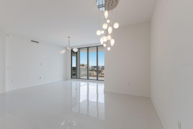 tiled empty room featuring expansive windows and a notable chandelier