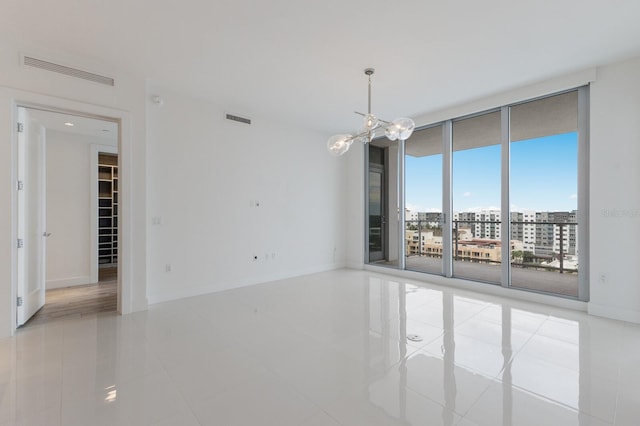 spare room with light tile patterned floors, expansive windows, and a chandelier