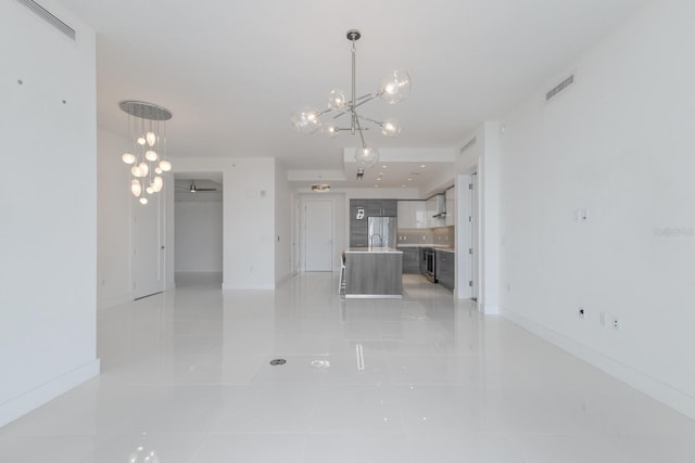 unfurnished living room with a notable chandelier, light tile patterned floors, and sink