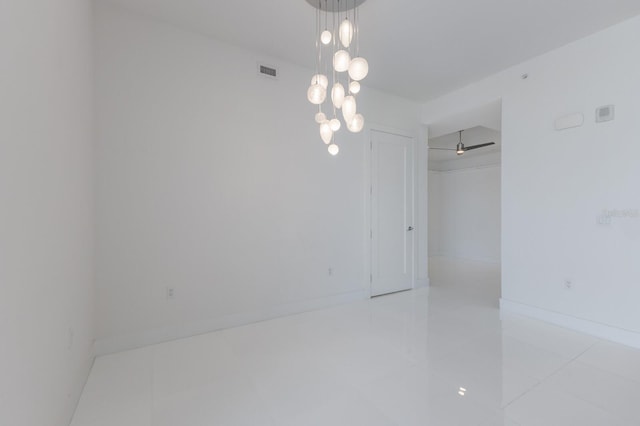 tiled spare room featuring an inviting chandelier