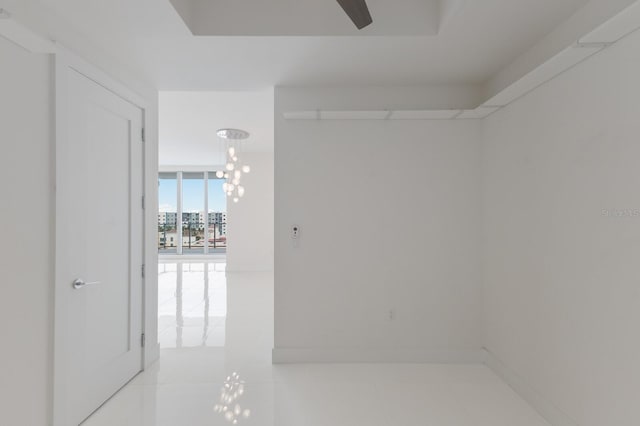 empty room with a notable chandelier, light tile patterned flooring, and expansive windows