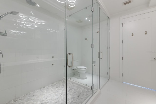 bathroom with a shower with door, toilet, and tile patterned floors