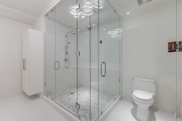 bathroom with tile patterned flooring, toilet, and a shower with shower door