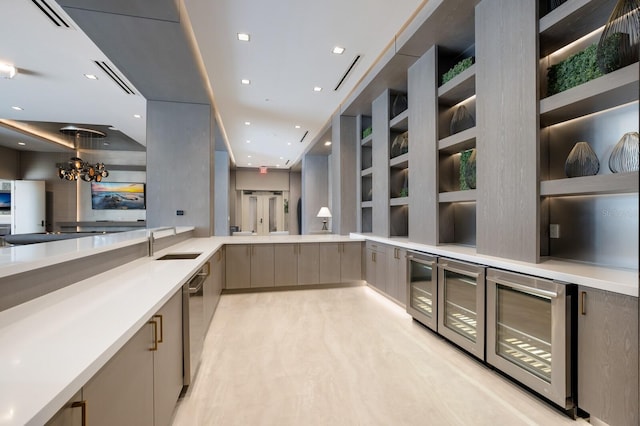 bar with hanging light fixtures, gray cabinetry, beverage cooler, sink, and a notable chandelier