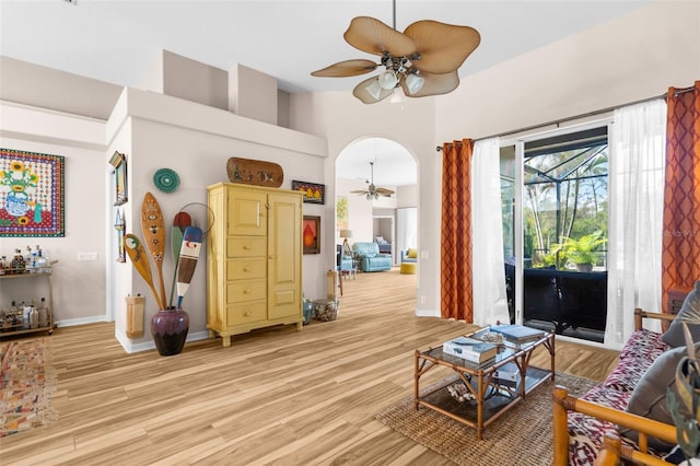 living room featuring a high ceiling, light hardwood / wood-style floors, and ceiling fan