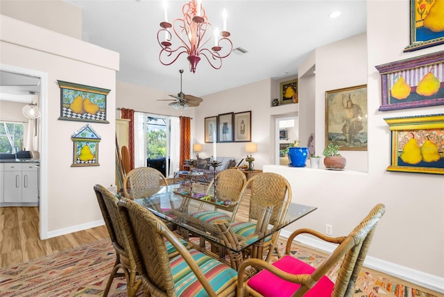 dining space featuring ceiling fan with notable chandelier and light hardwood / wood-style floors