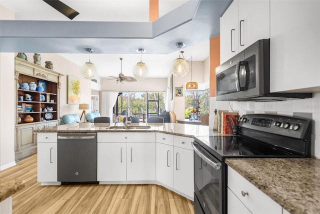 kitchen with sink, kitchen peninsula, pendant lighting, white cabinets, and appliances with stainless steel finishes