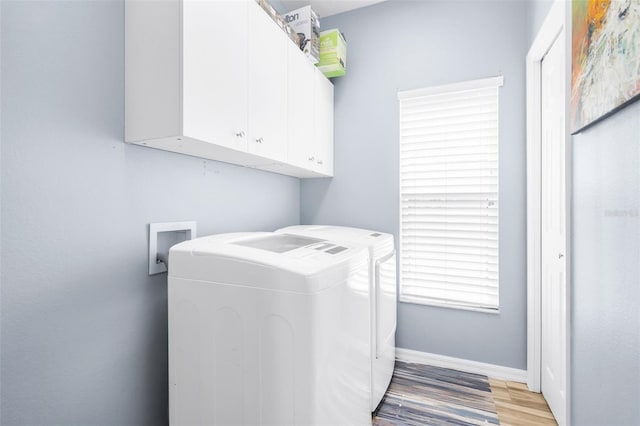 laundry room featuring washing machine and dryer, cabinets, and light wood-type flooring