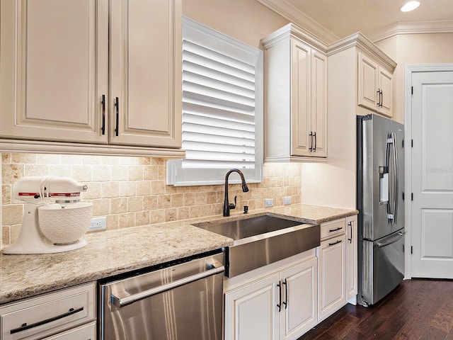 kitchen featuring dark wood-type flooring, sink, light stone countertops, ornamental molding, and appliances with stainless steel finishes