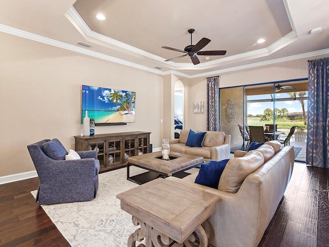 living room with ornamental molding, ceiling fan, a tray ceiling, and dark hardwood / wood-style floors