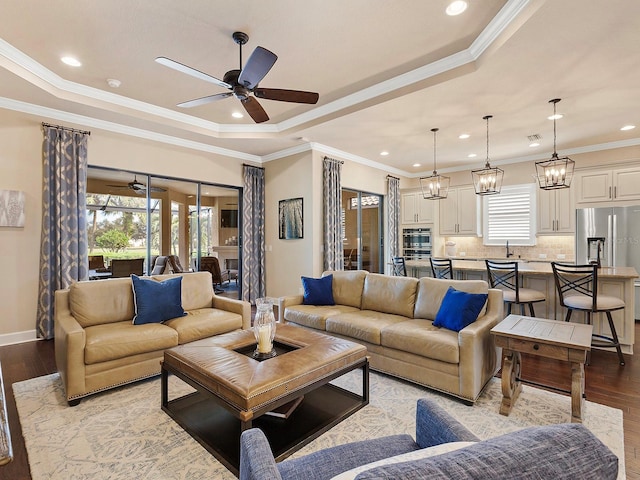 living room with a raised ceiling, crown molding, and light hardwood / wood-style floors