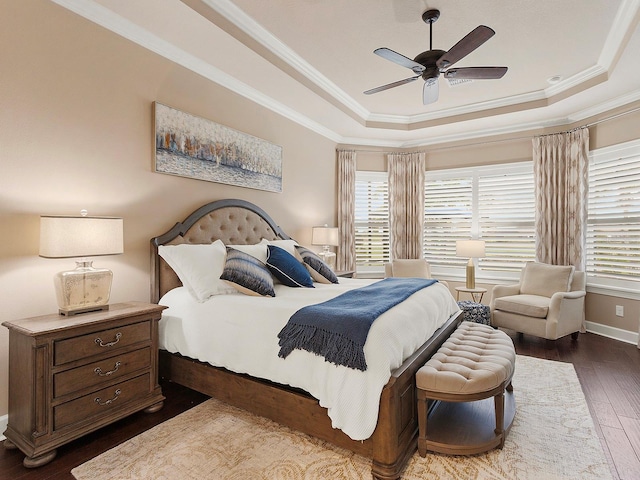 bedroom with ceiling fan, ornamental molding, a raised ceiling, and dark hardwood / wood-style flooring