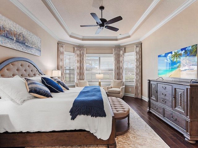 bedroom featuring ornamental molding, ceiling fan, dark wood-type flooring, and a tray ceiling