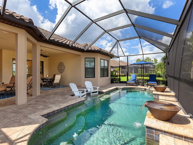 view of swimming pool featuring ceiling fan, a patio, a lanai, and pool water feature